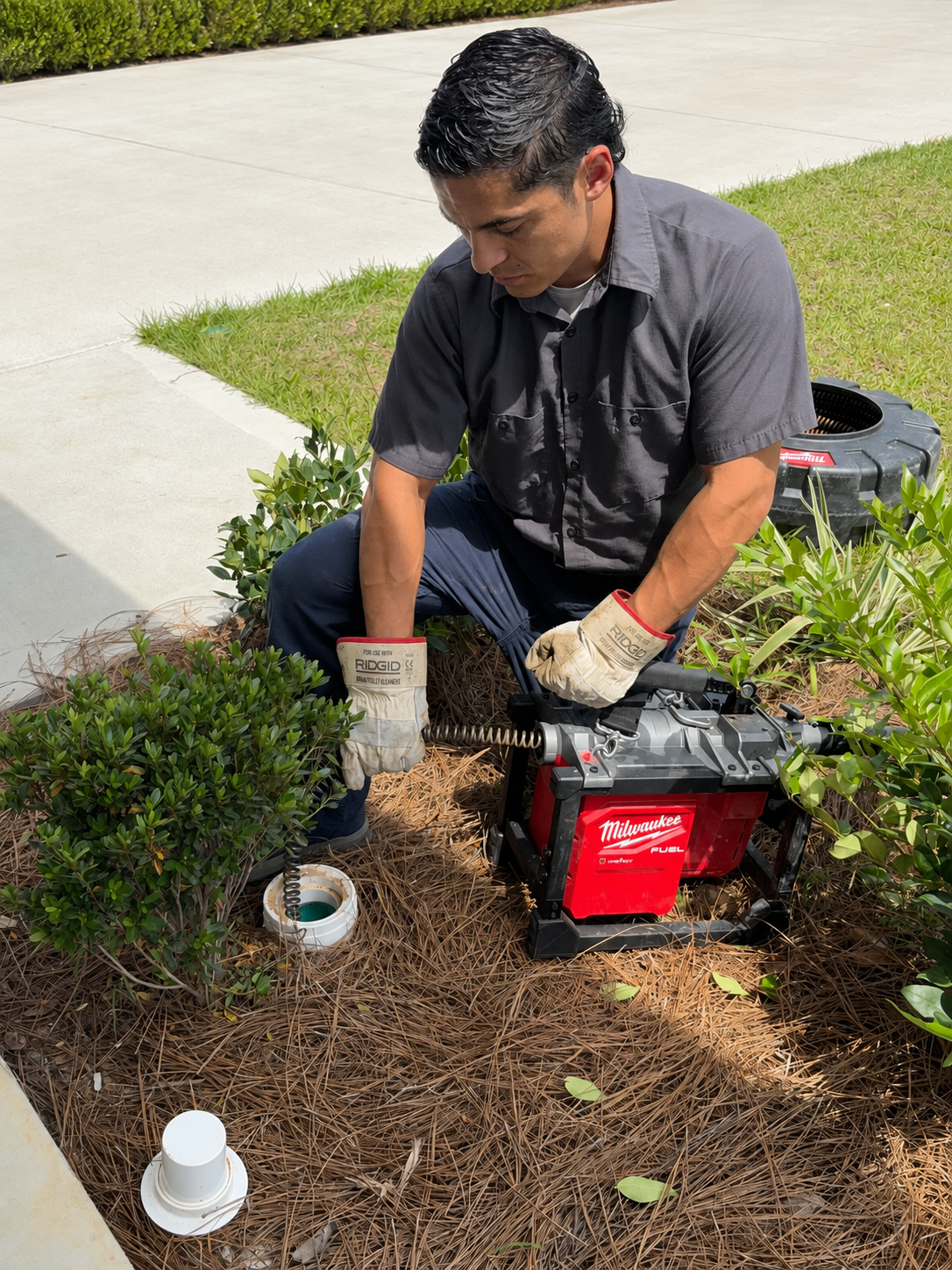 Master plumber clearing an outdoor drain line with professional drain-cleaning equipment in Pensacola, Florida