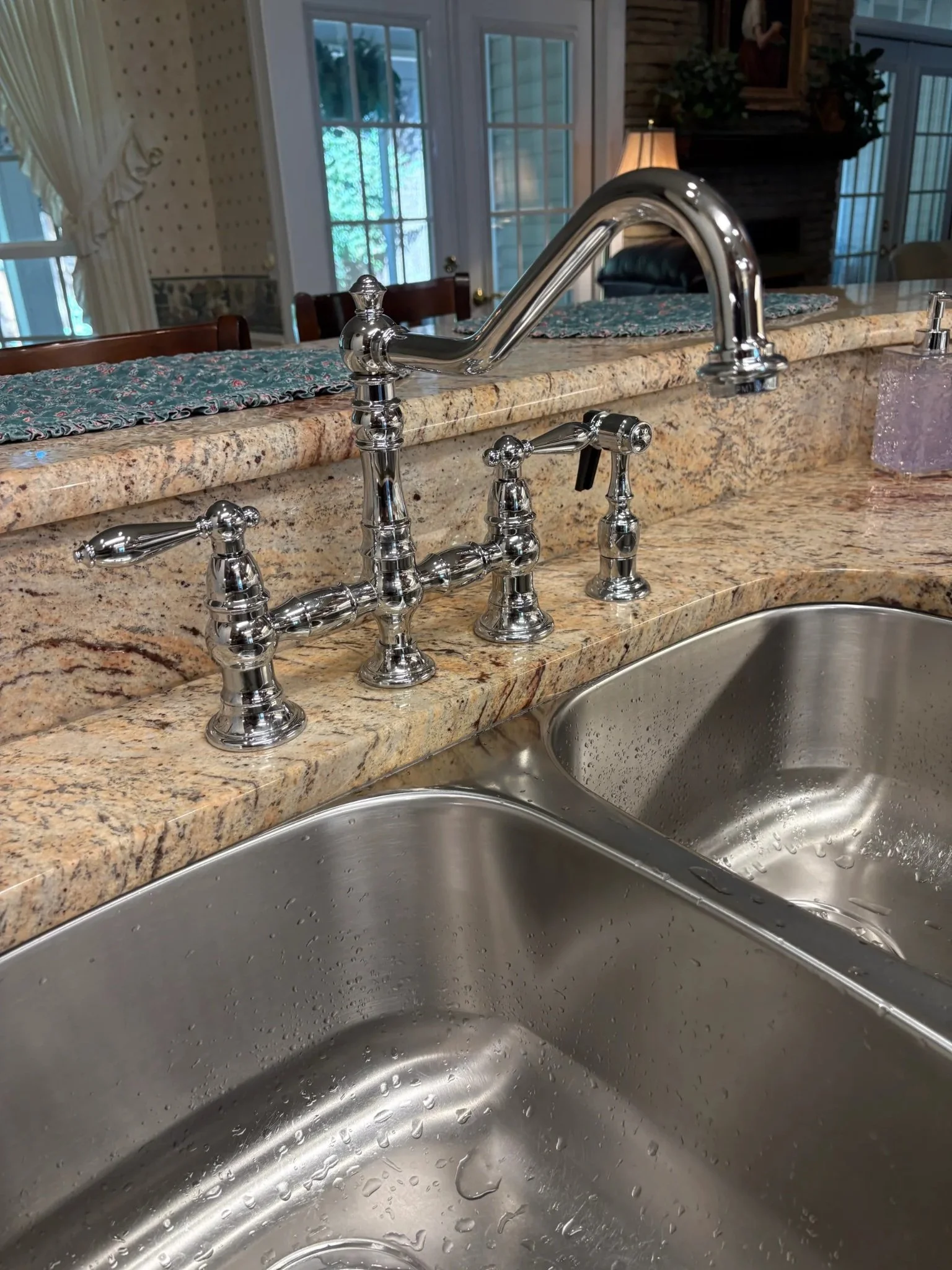 Chrome kitchen faucet, sprayer and double-basin sink installed during a Pensacola kitchen plumbing upgrade