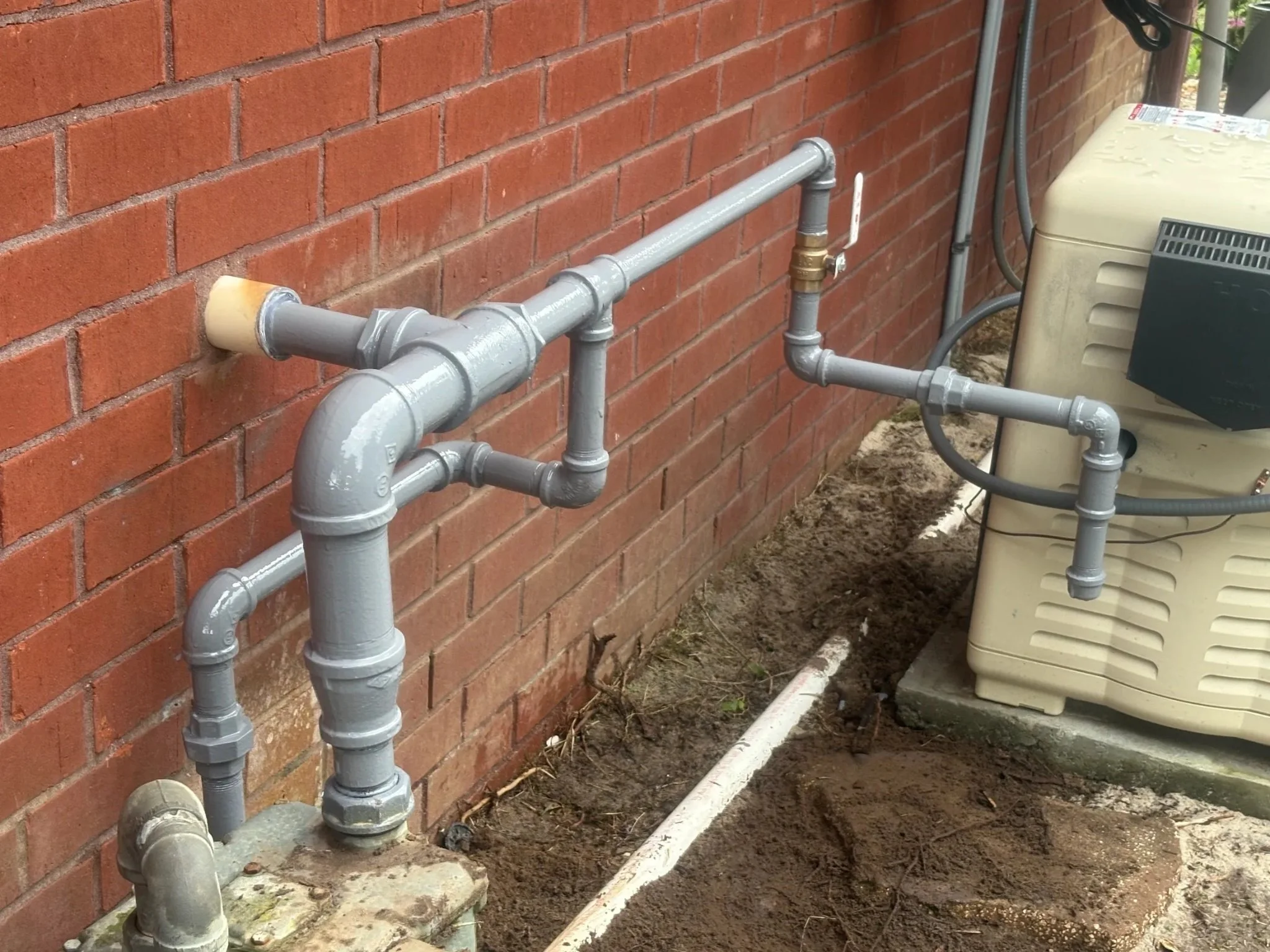Exterior natural gas piping and shutoff valve installed for a Generac standby generator in Pensacola, Florida