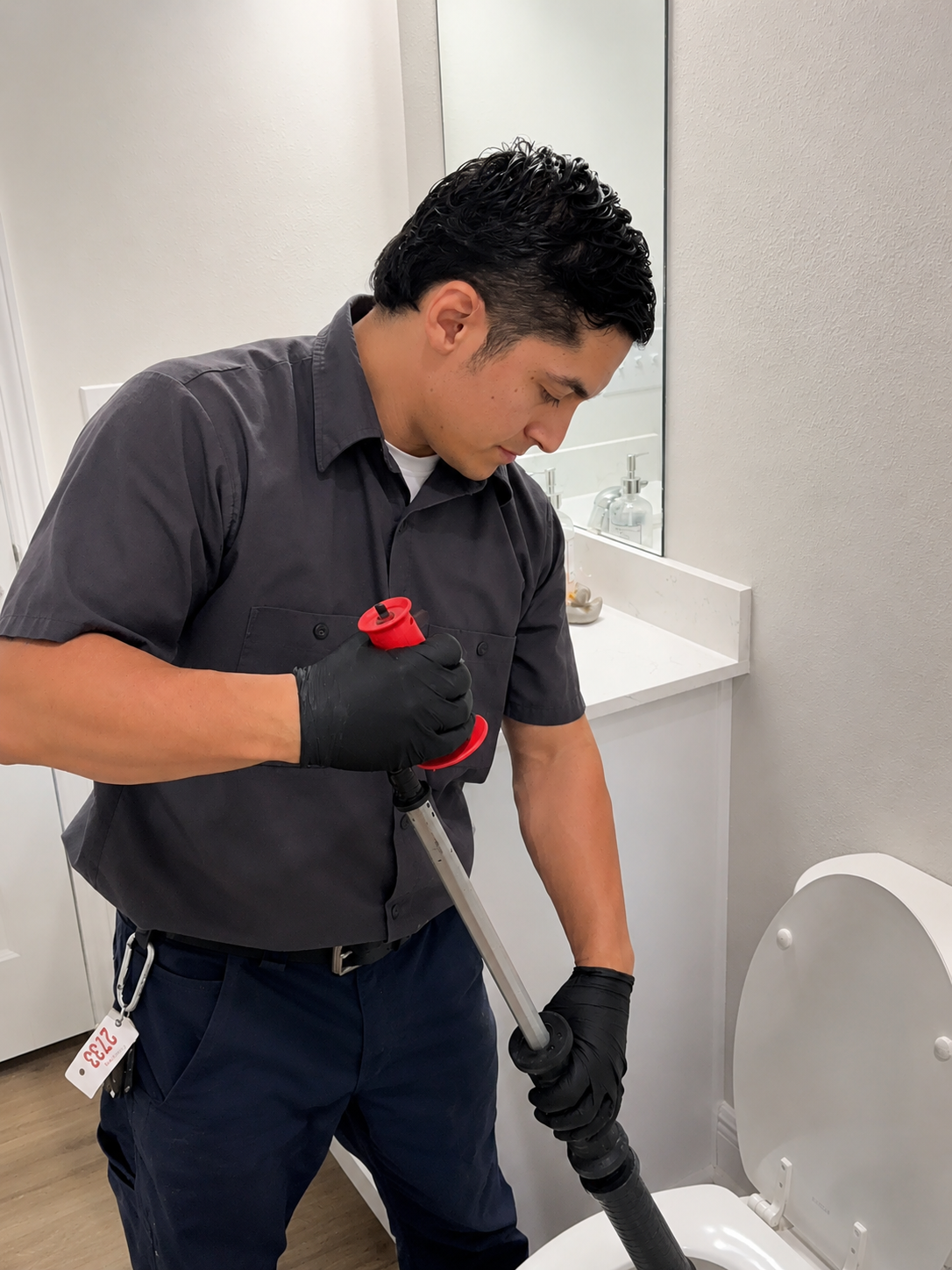 Master Plumber using a toilet auger to clear a clogged toilet in Pensacola, Florida