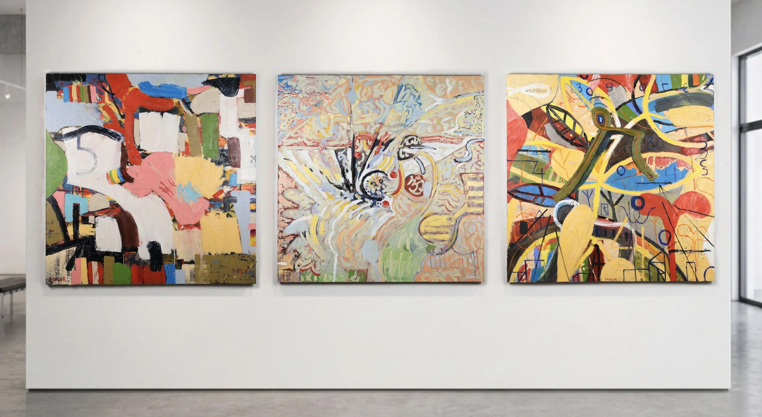 Three large abstract paintings hung side by side on a gallery wall, featuring vibrant colors and dynamic brushstrokes.