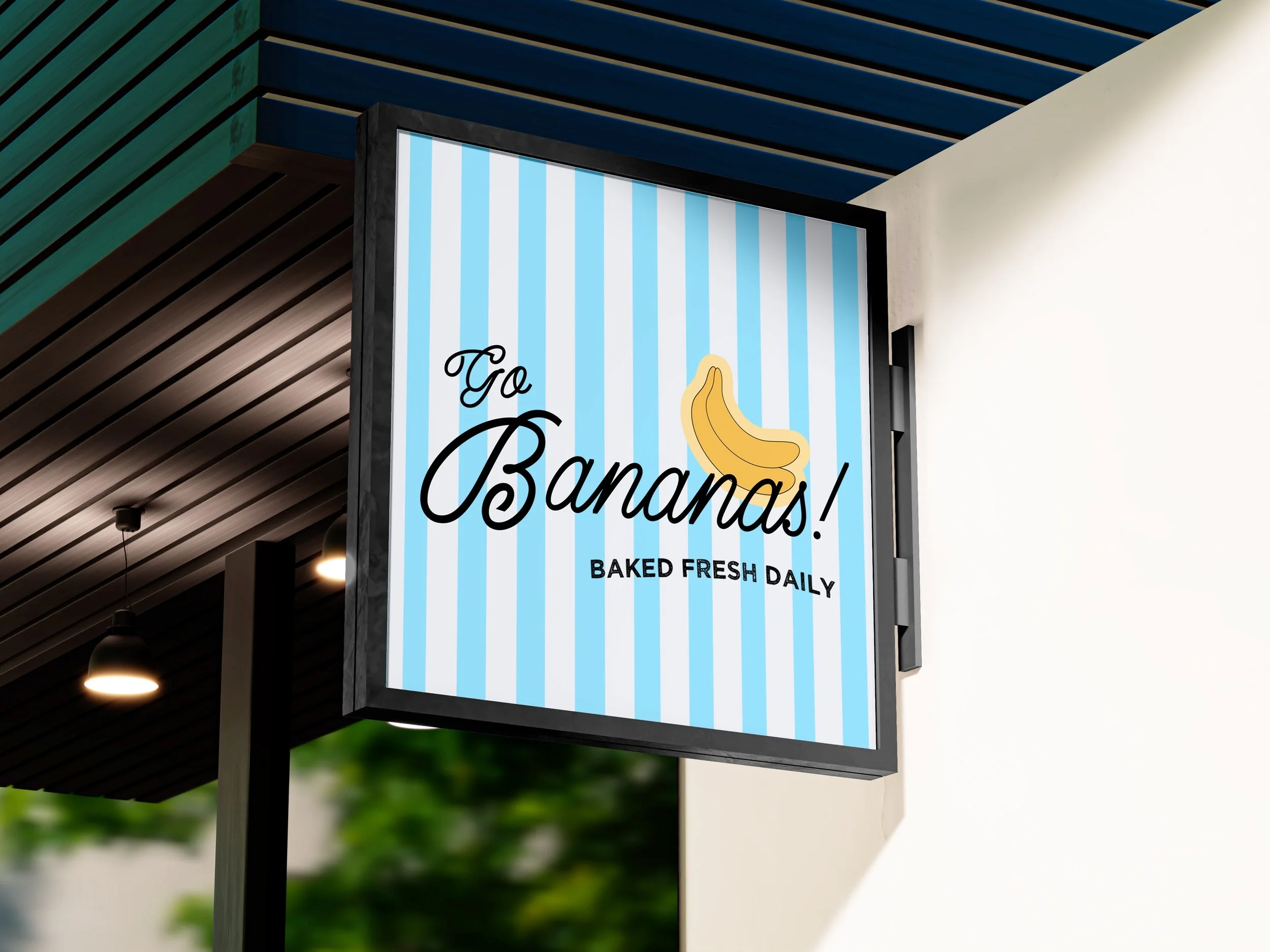 Signboard for a bakery named Go Bananas with a banana illustration and the text Baked Fresh Daily, blue and white striped background.