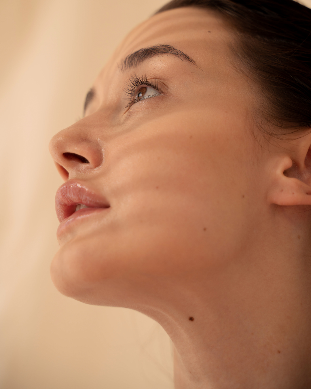 Close-up of a woman's face showing her nose, lips, and eye, with smooth skin and minimal makeup.