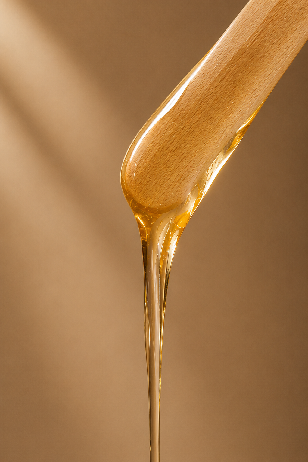 Maple syrup being poured from a wooden spoon.