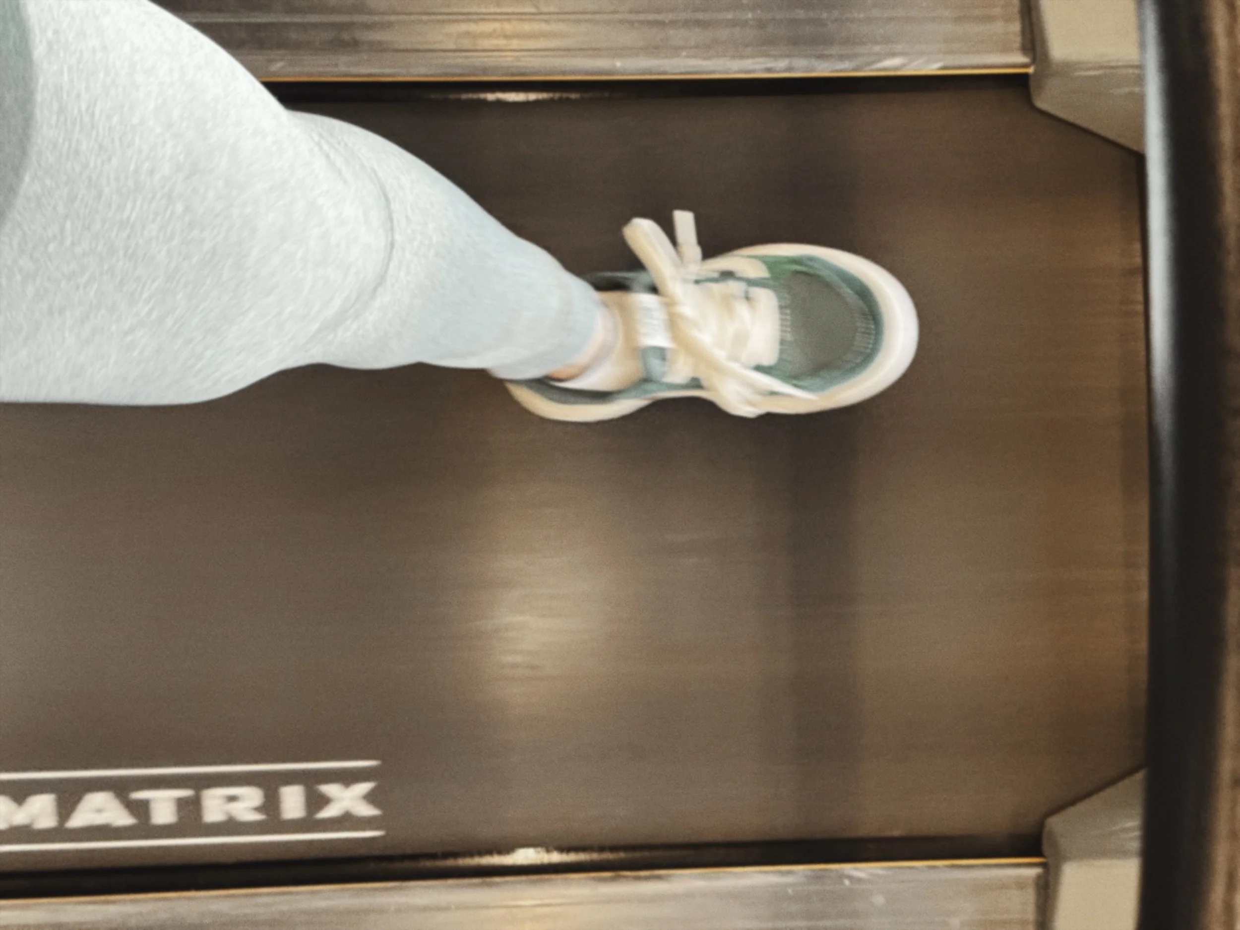 A person's foot in a sneaker stepping onto a moving walking pad.