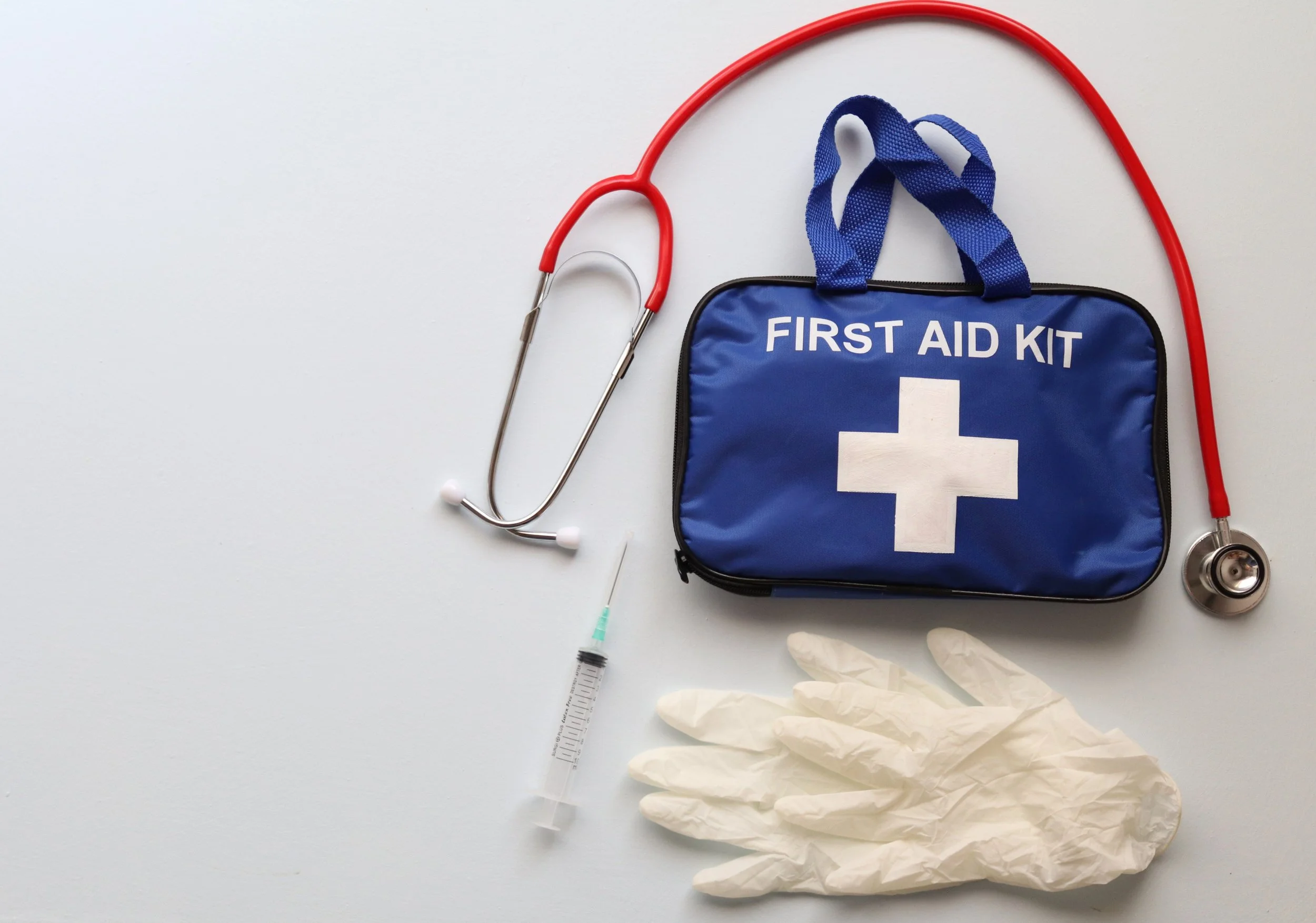 First aid kit, stethoscope, syringe, gloves, and medical supplies on a white background.