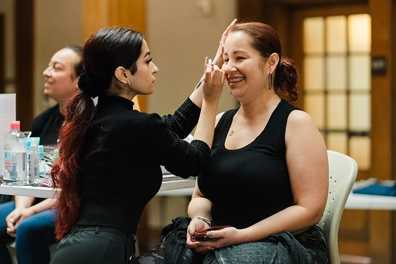 Makeup artist applying makeup on a woman's face in a salon or studio setting