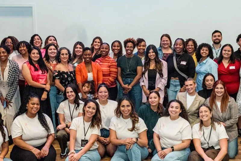 Group of diverse women and men posing for a photo in a room.