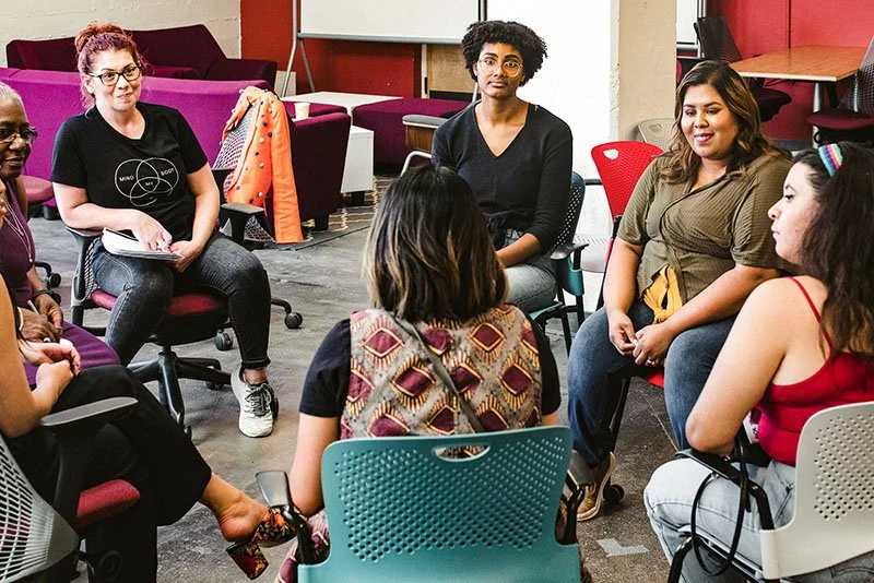 group of diverse women having a discussion in a casual office setting.