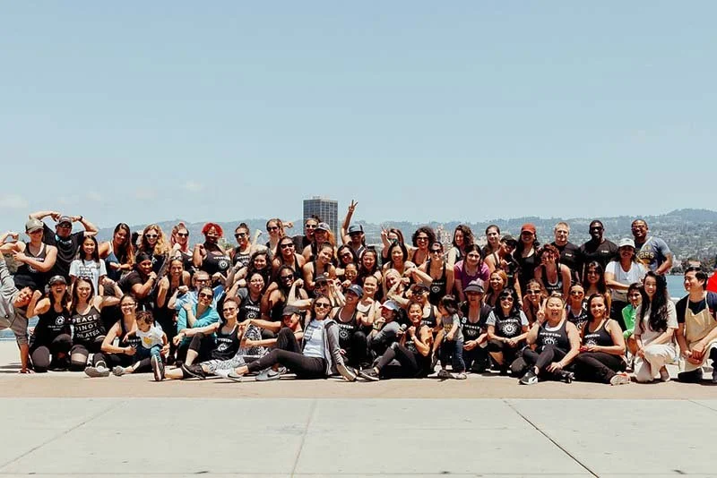 Group of diverse people posing for a photo outdoors with city and hills in the background.