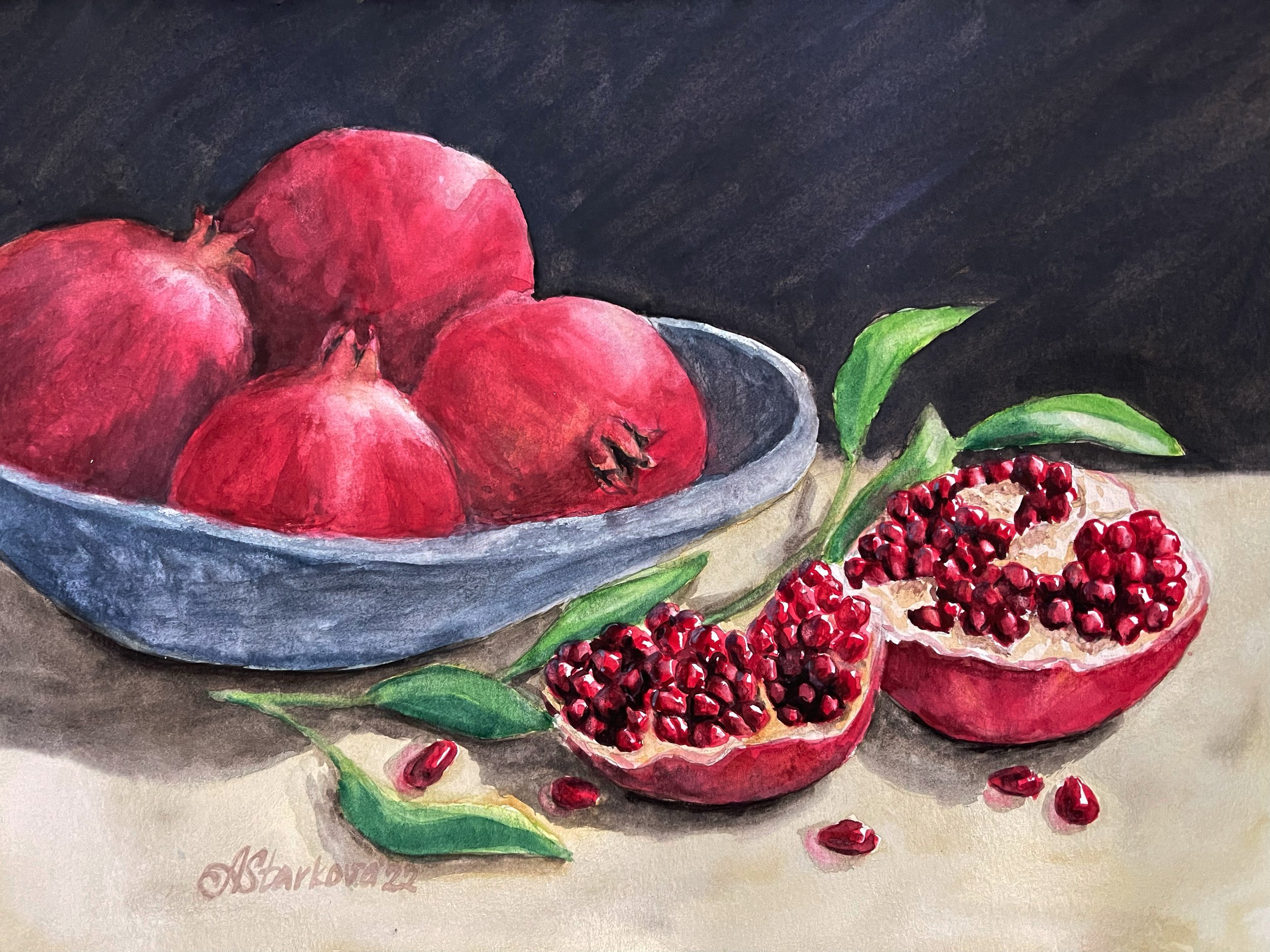 A still life composition featuring a bowl of pomegranates on a table and a black background, green leaves and red pomegranate seeds scattered around.