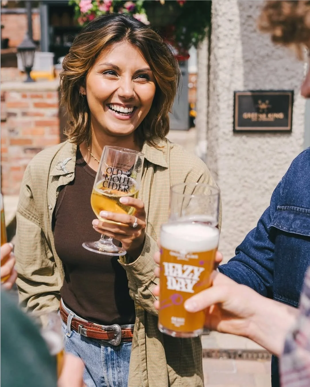 Group of people enjoying drinks outdoors, smiling, and engaging in conversation.