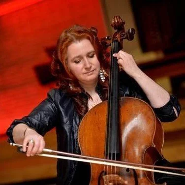 Woman playing the cello on stage with a focused expression.