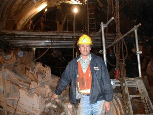 Principal Charles Merguerian standing in front of the disarticulated cutter head of the Queens Tunnel TBM after hole-thru, 1999.