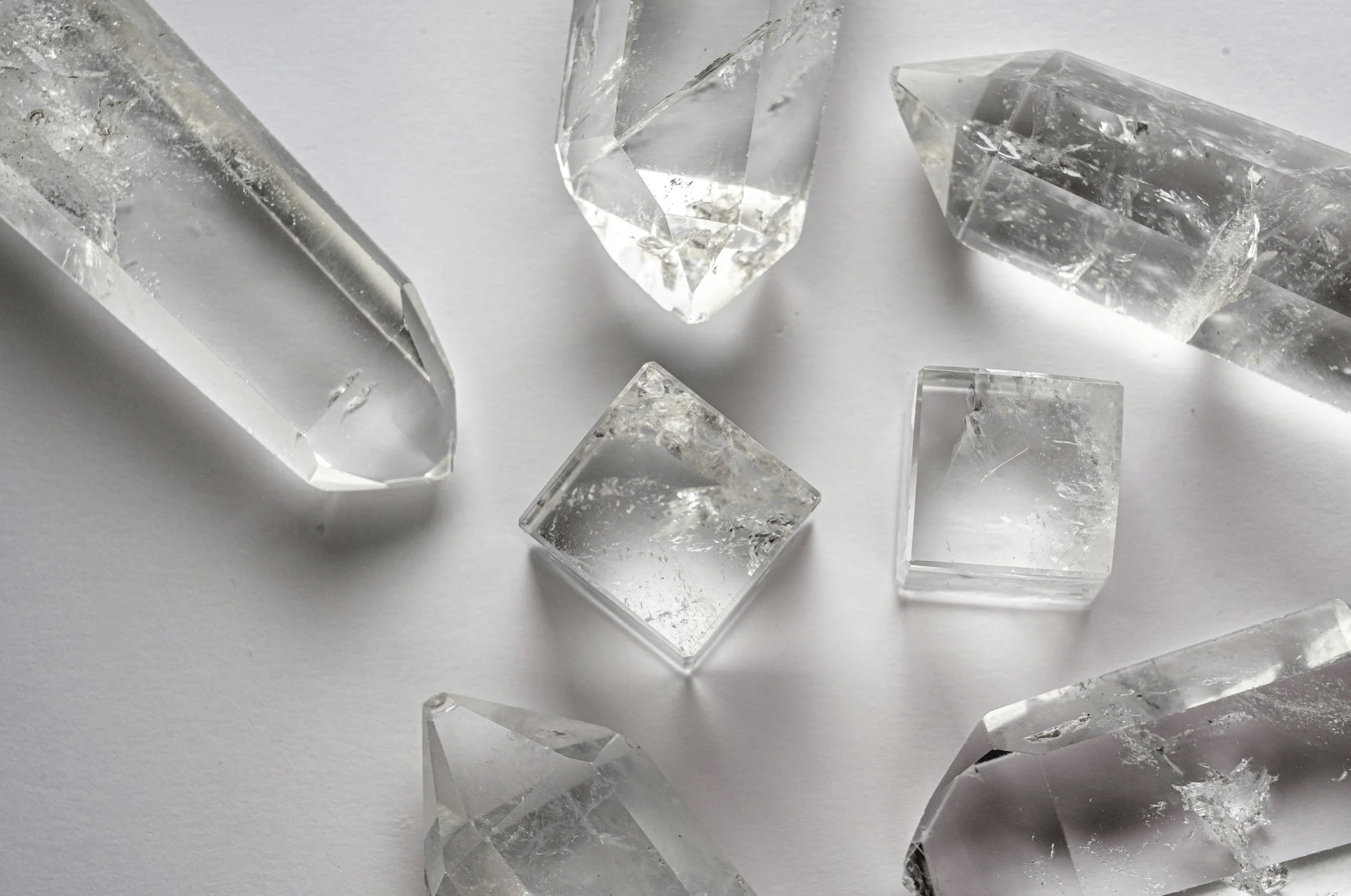 Close-up of several clear quartz crystals with a white background.