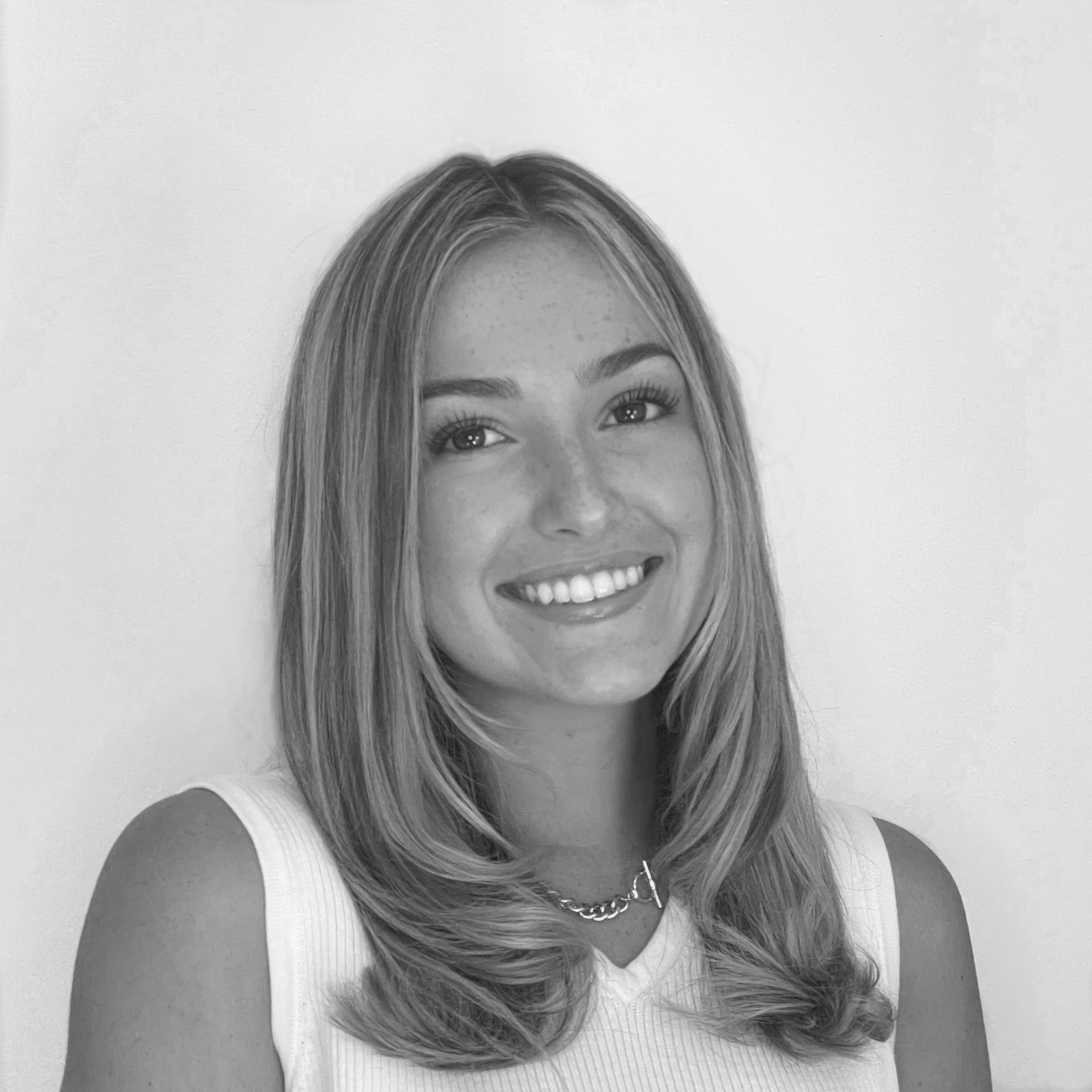 Black and white photo of a smiling young woman with straight hair, wearing a necklace.