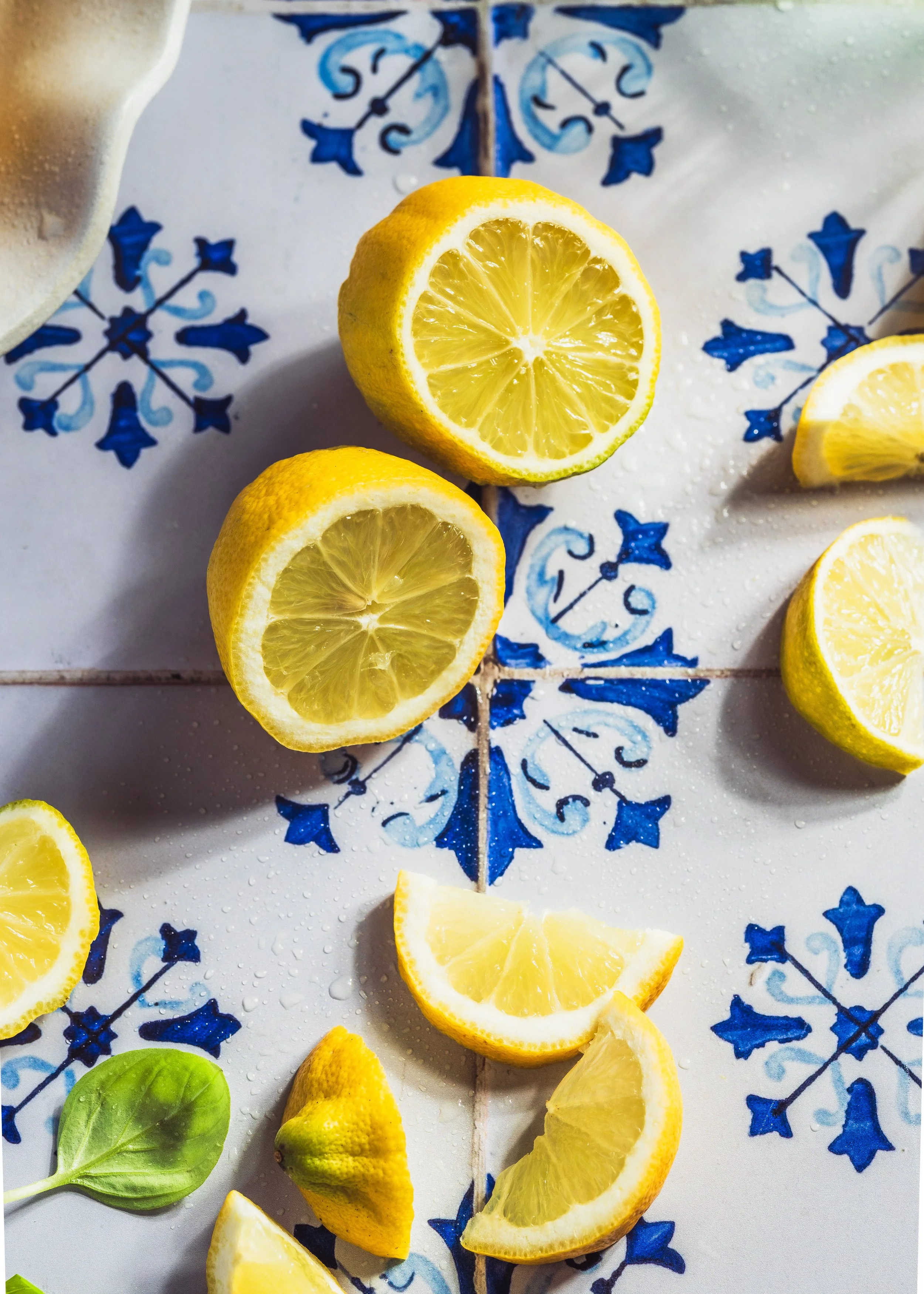 Schnittfächer mit Zitronen und Limetten auf einem blauen und weißen Fliesentisch.