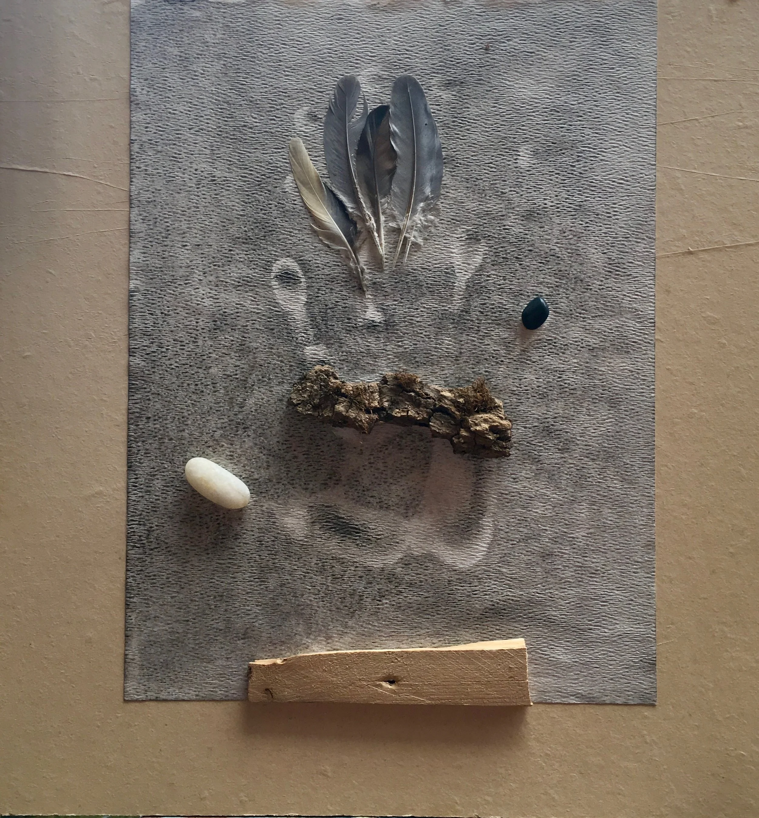  Hand Print , 2024. Bark, wood, pebbles, feathers, India ink, paper, oil on masonite – 12" X 9" X 1.5"