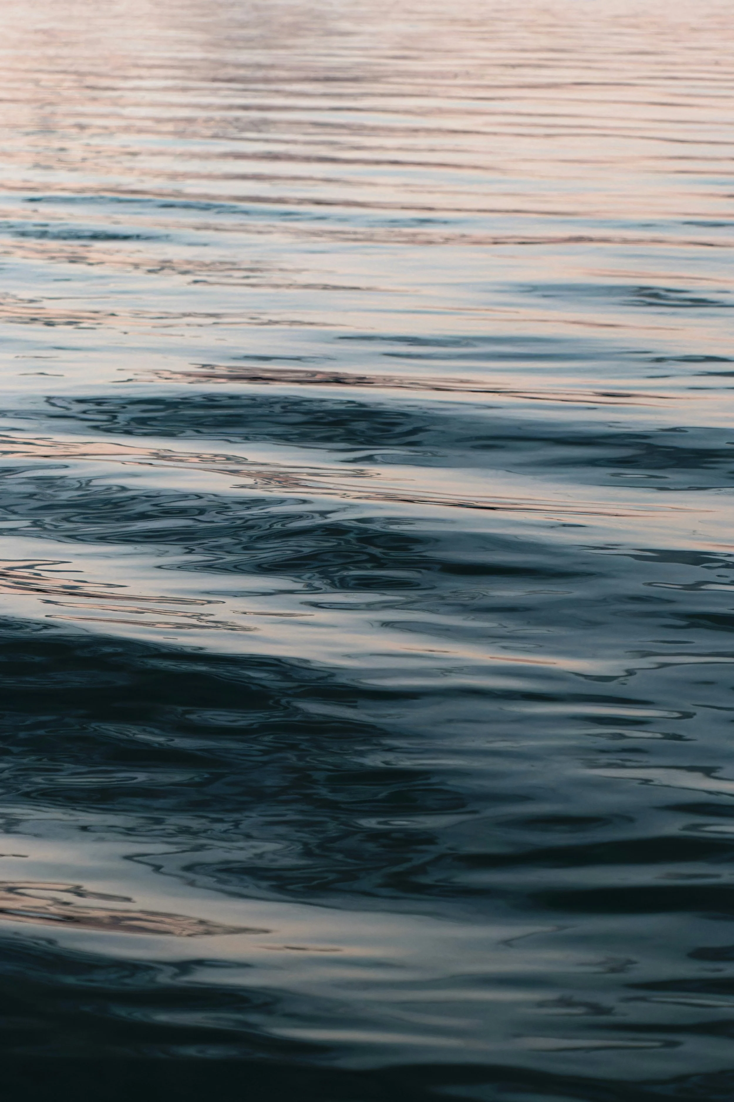 Calm water surface with gentle ripples during sunset or sunrise.