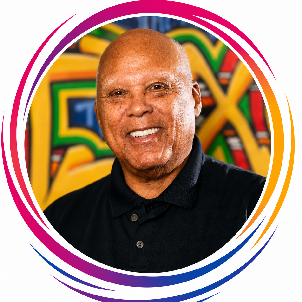 Smiling man with short bald head wearing a black collared shirt, standing in front of colorful graffiti art.