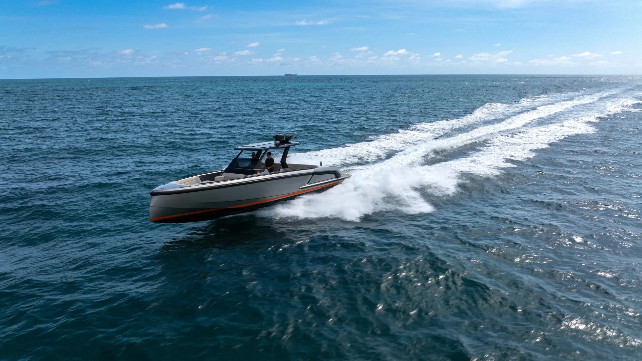 A motorboat speeding through the ocean leaving a trail of white foam behind it on a sunny day with a blue sky and some clouds.