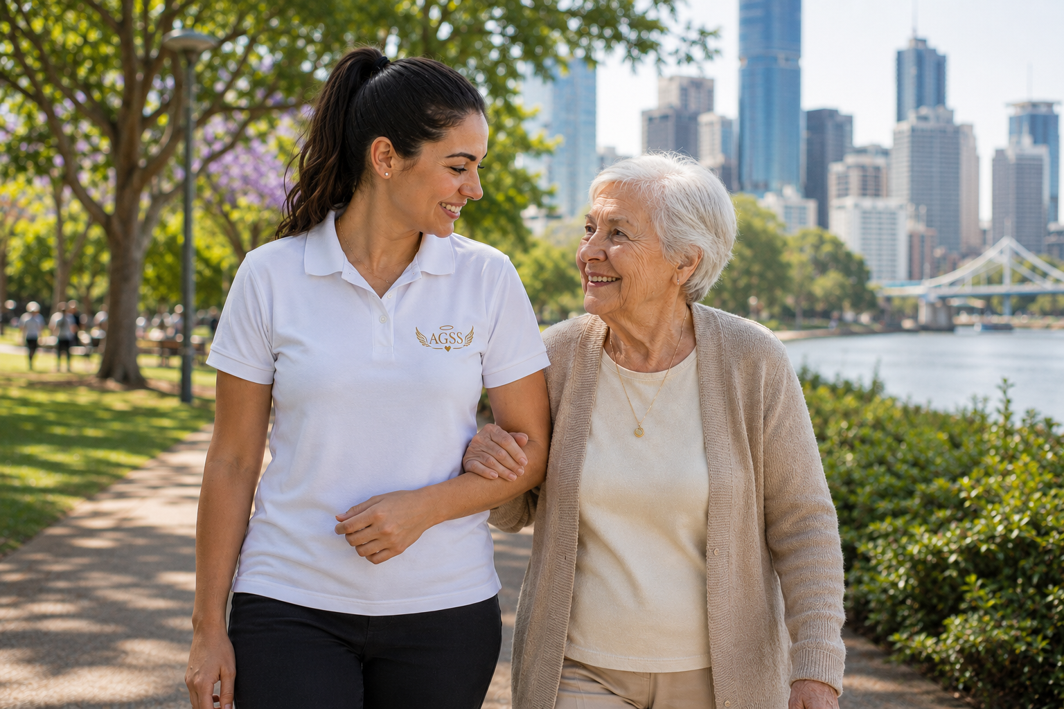 A young woman and an elderly woman walking together in a park, smiling and holding each other’s arms.