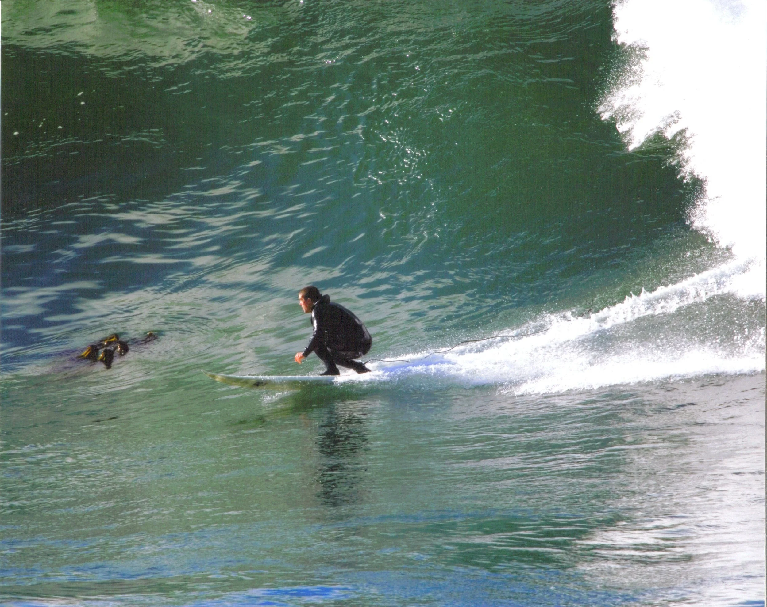 Person in a wetsuit riding a wave on a surfboard in the ocean.