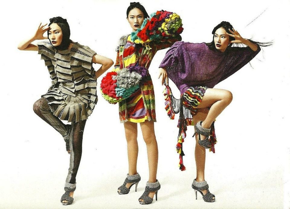 Three women in colorful, fashionable outfits posing against a white background.
