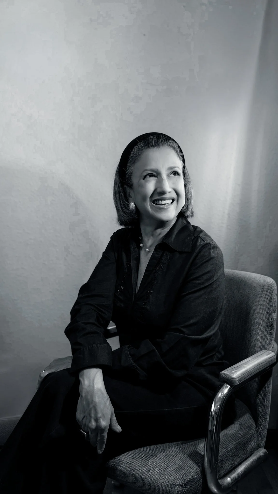 Black-and-white portrait of a smiling woman seated in an armchair.