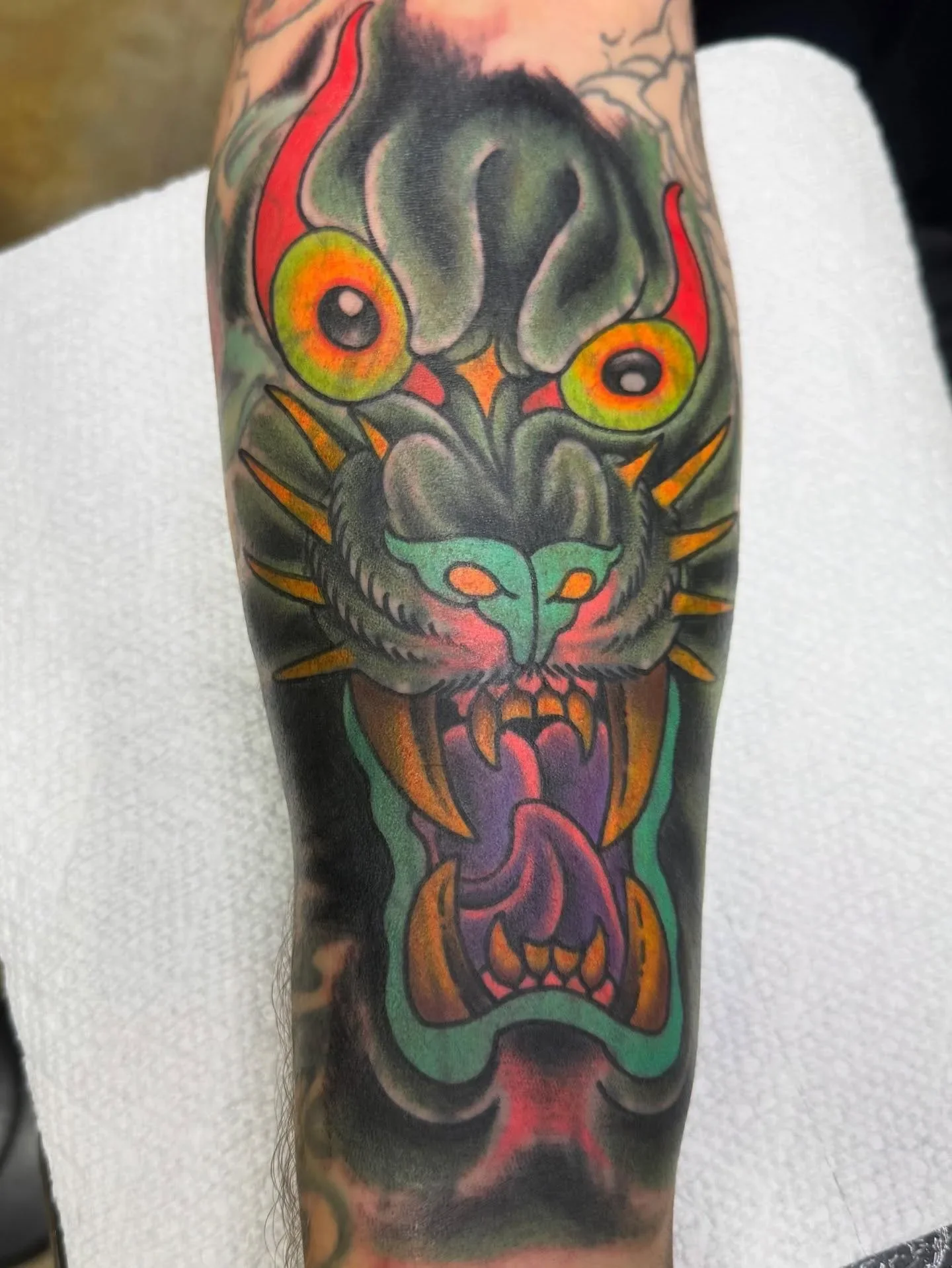 :Vibrant color traditional panther demon face blast overwith large orange eyes and open mouth. Psychedelic neo-traditional predator tattoo with bold black background by Brett Semrick.