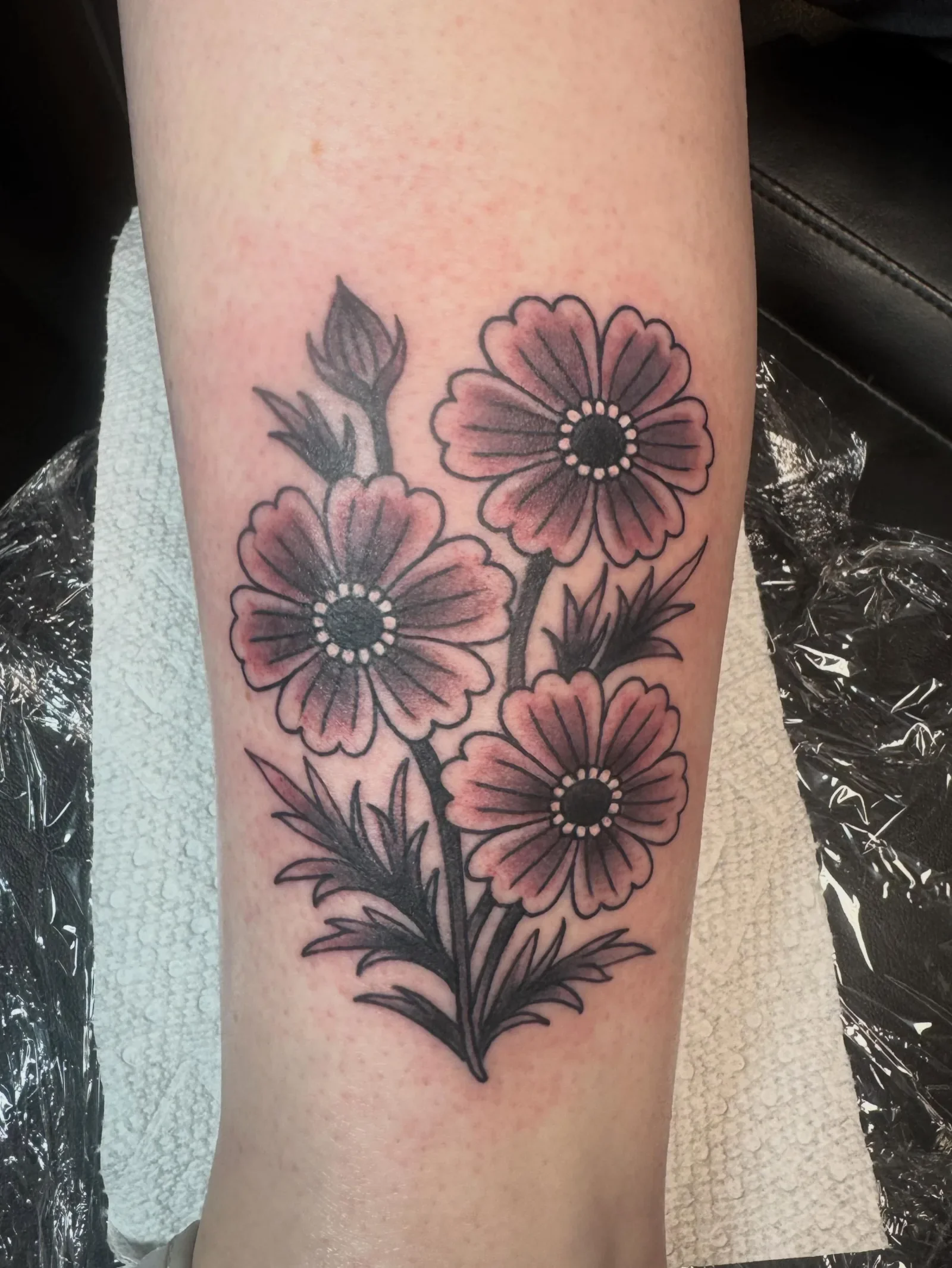  Traditional style cosmos flowers in black and grey. Three bold blooms with whip-shaded leaves and buds. Delicate yet timeless traditional floral tattoo by Brett Semrick at BrettSemrick.com.