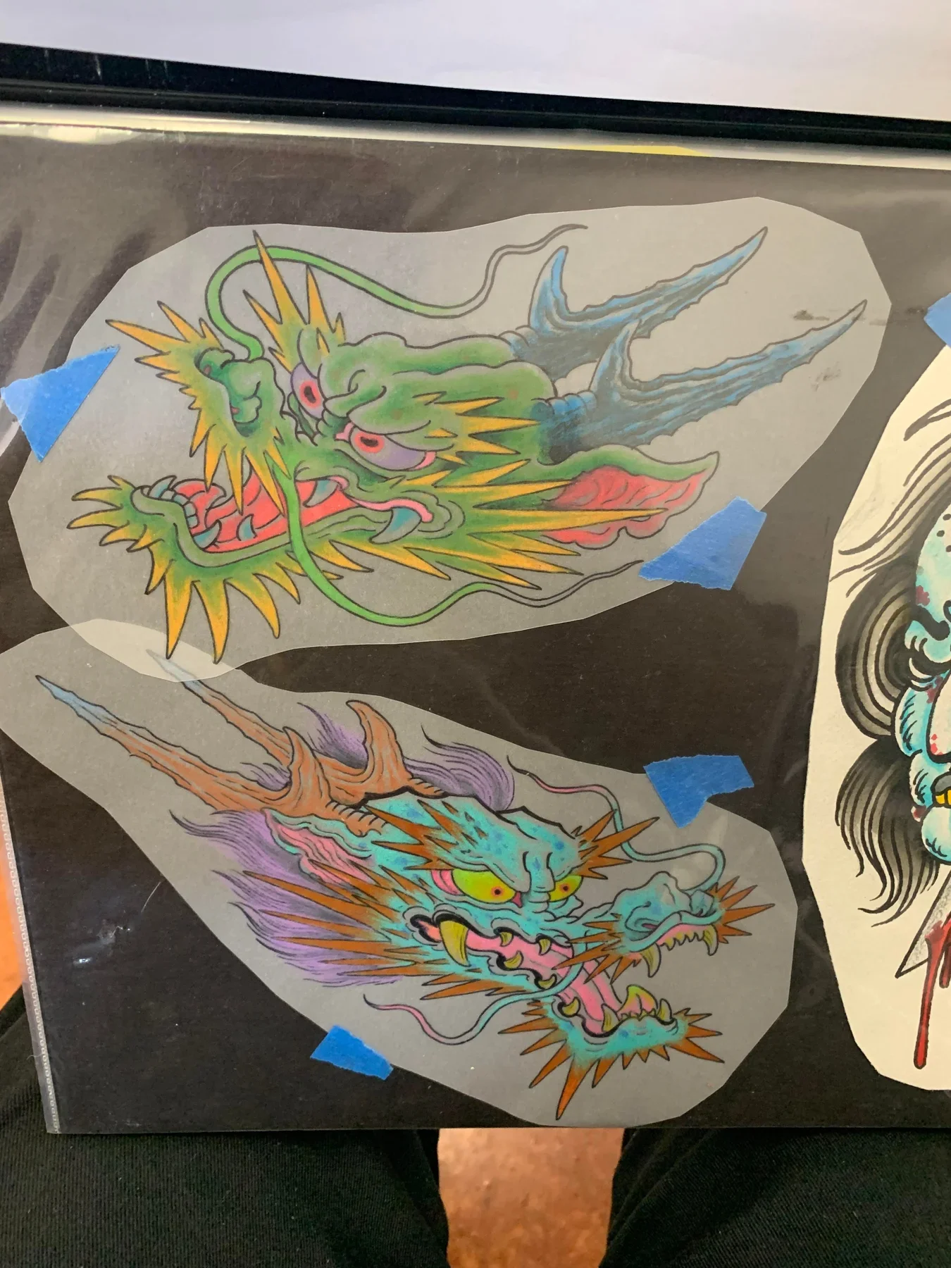  Pair of traditional Japanese ryu dragon head studies. Top green dragon with red eyes and blue horns. Bottom teal dragon with yellow eyes, orange mane and purple smoke. Colored pencil and ink on tracing paper, traditional palette exploring dragon exp