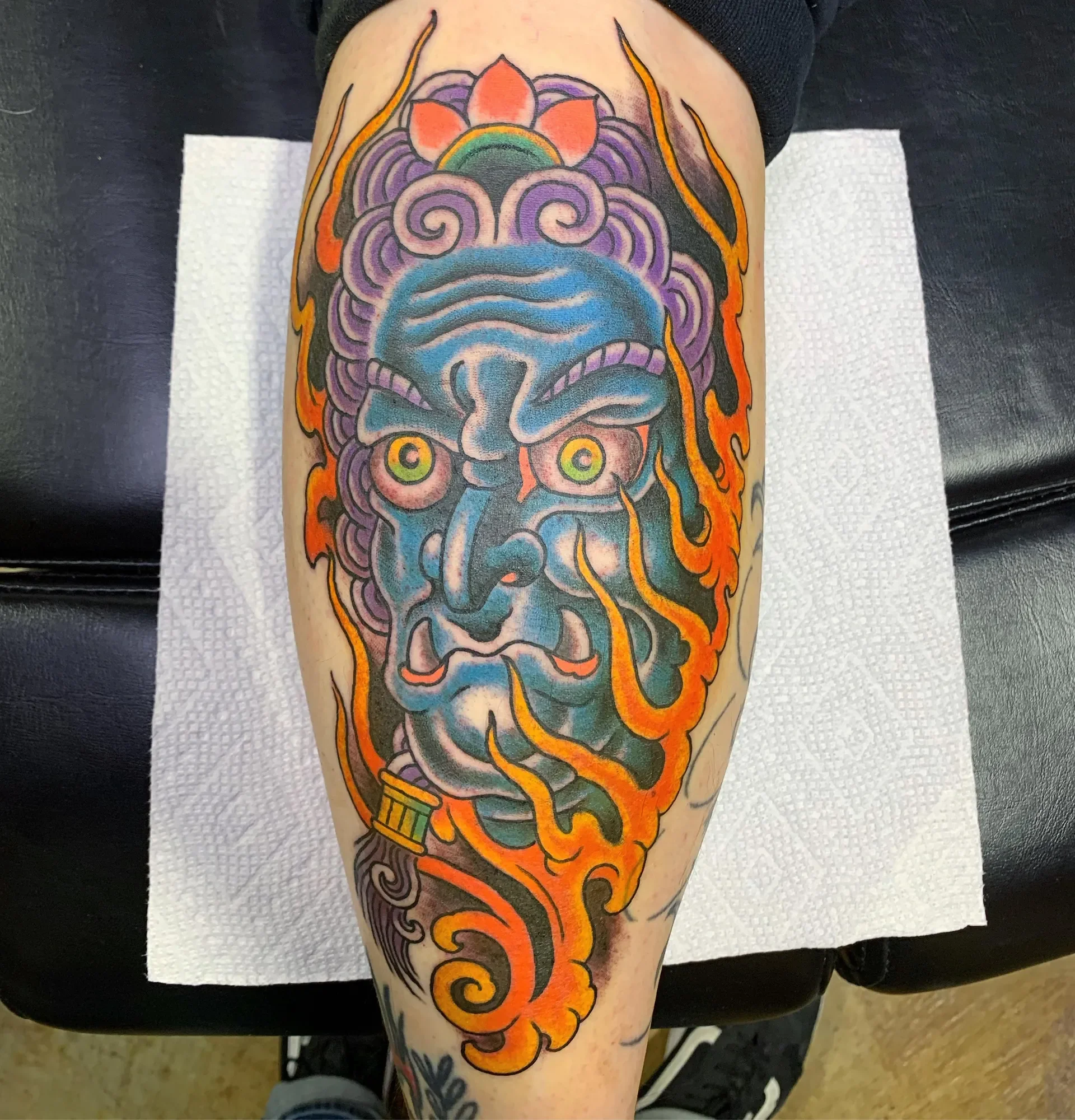 Fudo-style demon head with  blue skin, flame tendrils, and heavy color. Japanese street style with bold modern palette. Calf.