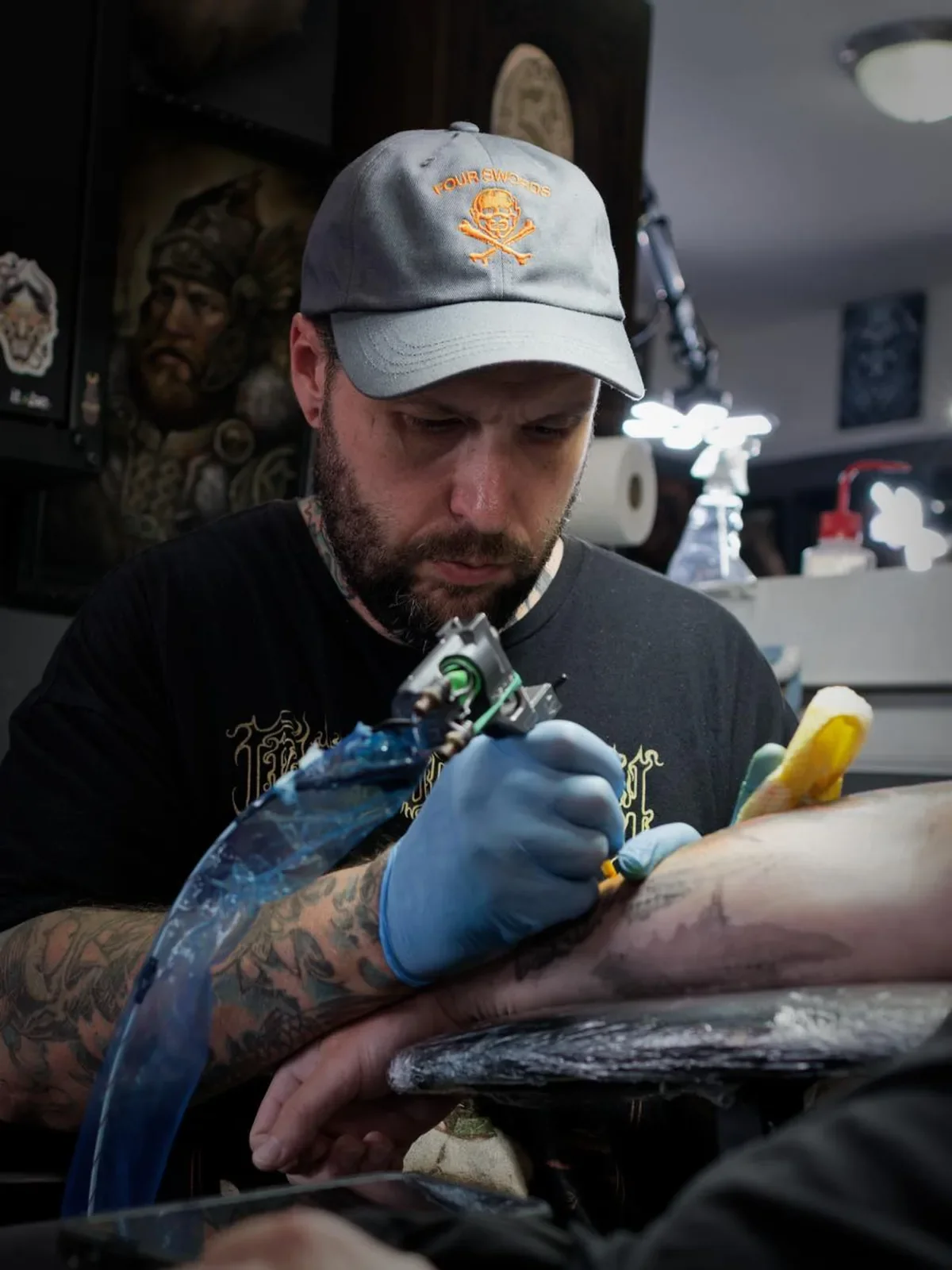 Tattoo artist tattooing a person's arm in a tattoo shop.