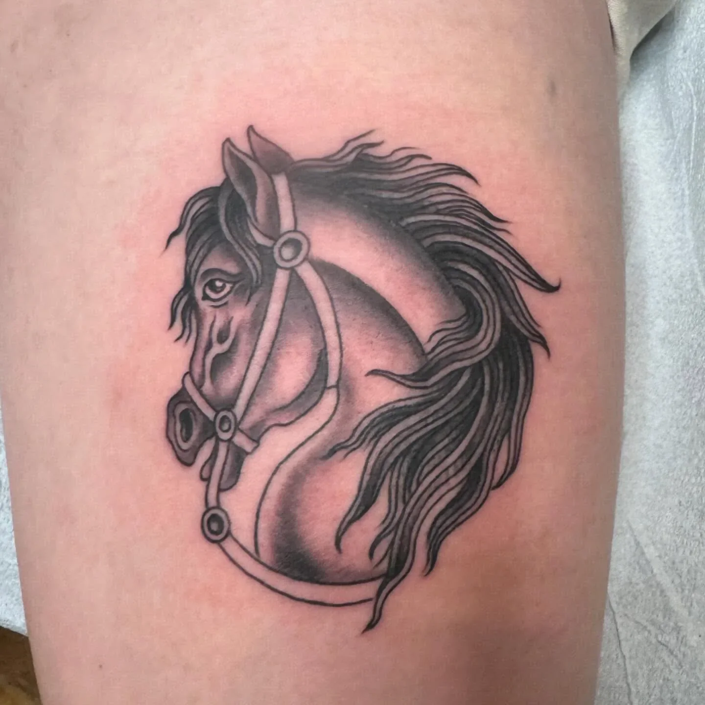 Black and grey traditional horse head tattoo with flowing mane and bridle. Classic equestrian traditional work with smooth whip shading by Brett Semrick.
