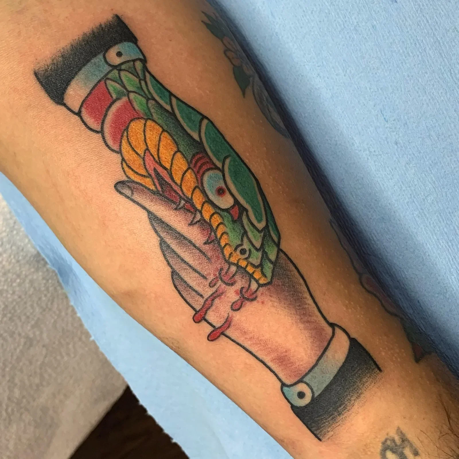 Classic "trust no one" motif — green and gold snake biting a gentleman's hand, blood drip in bold trad.
