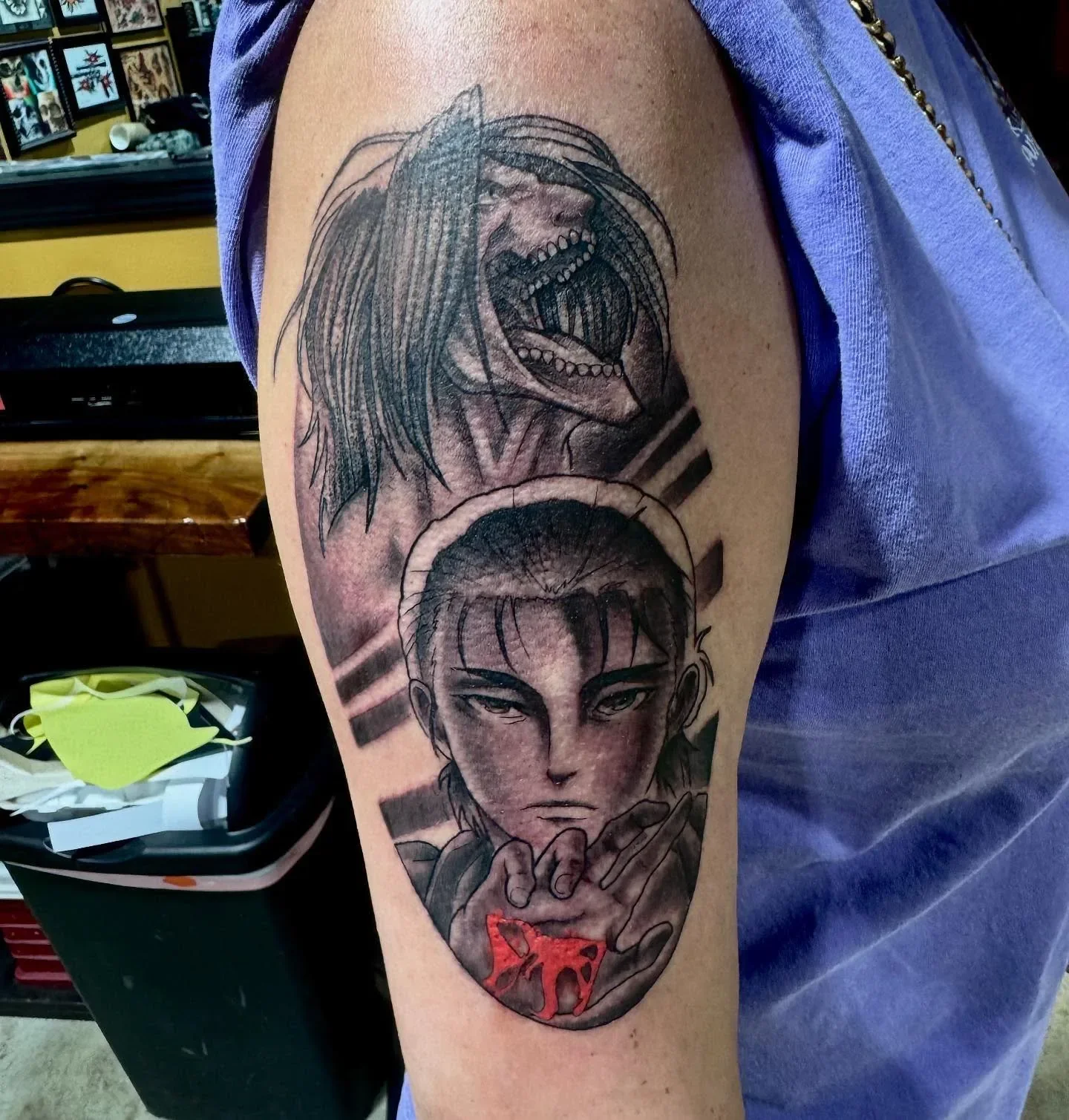Anime tattoo of Eren Yeager from Attack on Titan featuring his Titan roar above human form holding blood in hand. Black and gray with striking red accent by Brett Semrick.