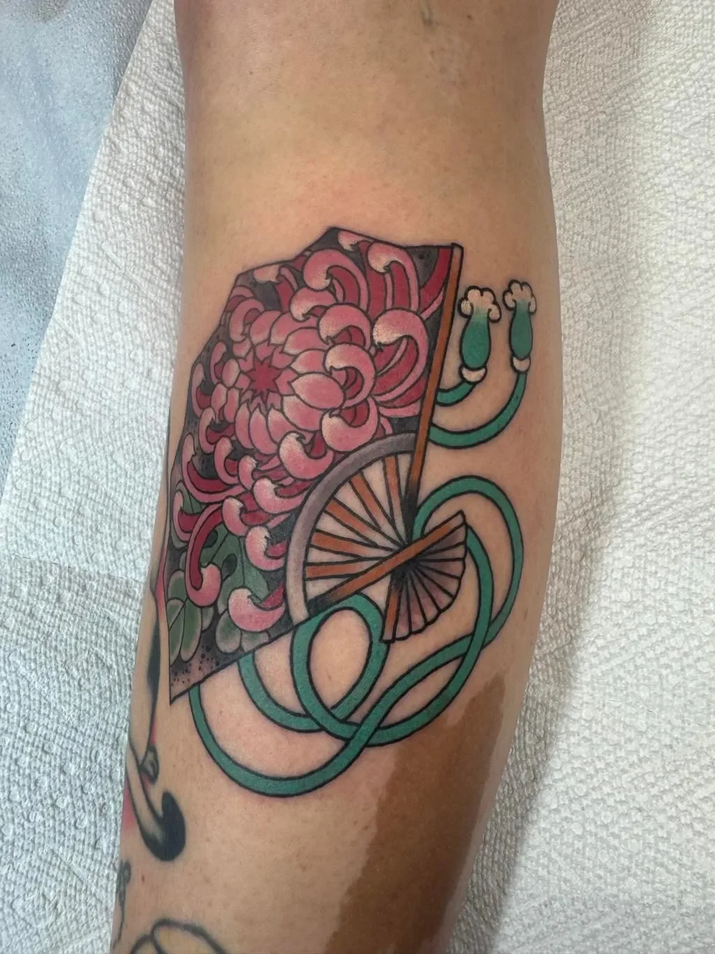 Japanese ogi fan tattoo with pink chrysanthemum by Brett Semrick in San Diego. Traditional irezumi kiku flower, sensu fan with bold color.
