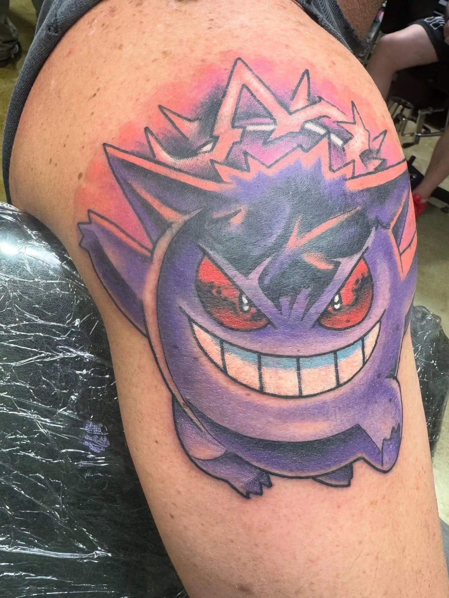 Vibrant color traditional Gengar Pokemon tattoo - purple ghost with red eyes and pink aura. Bold anime tattoo cover-up transformation by Brett Semrick in San Diego.

