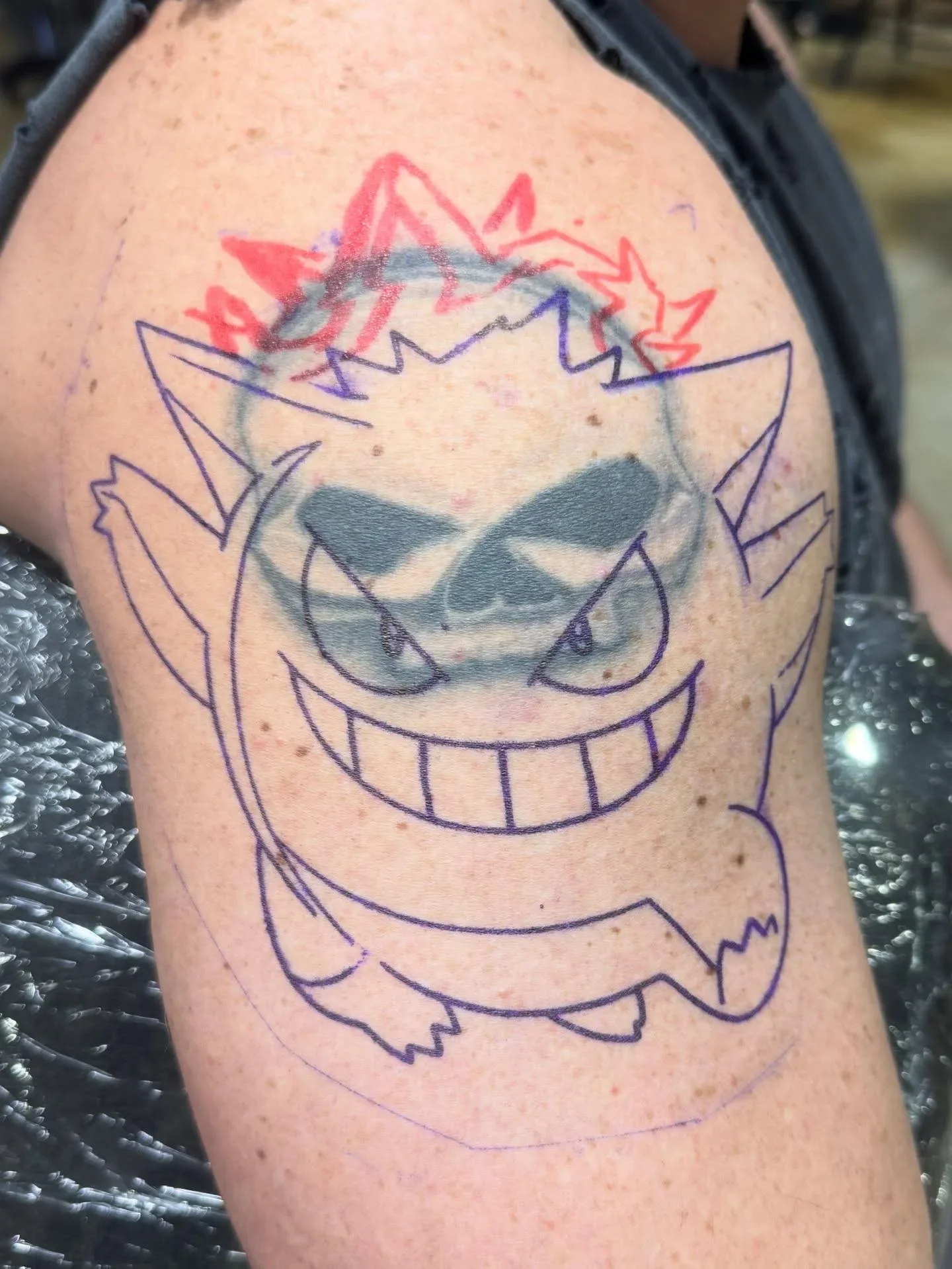 Traditional Gengar cover-up in progress - purple stencil over faded old tattoo, showing how Brett Semrick transforms old work into bold color traditional Pokemon tattoos.
