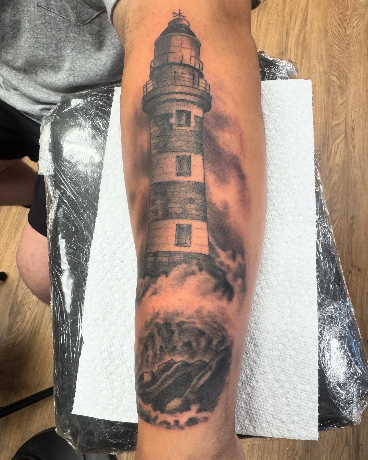  Full forearm lighthouse on rocky coast in a storm. Atmospheric black and grey realism.
