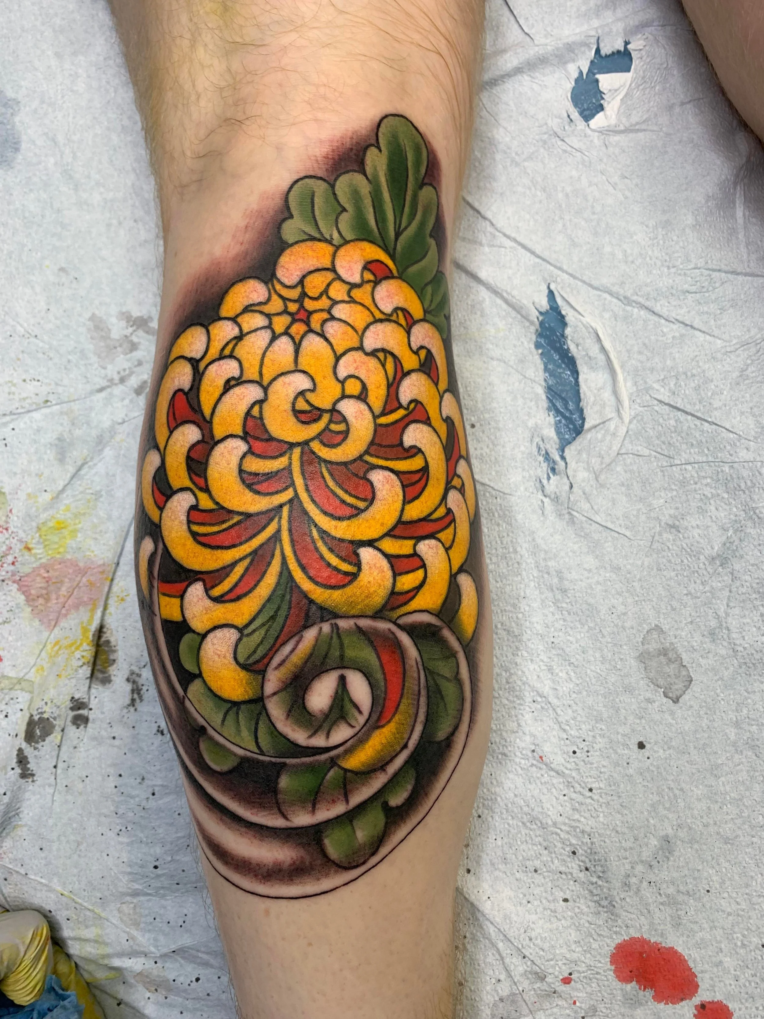 Traditional Japanese chrysanthemum tattoo by San Diego artist Brett Semrick. Bold color kiku flower, calf placement, Japanese tebori-inspired style.
