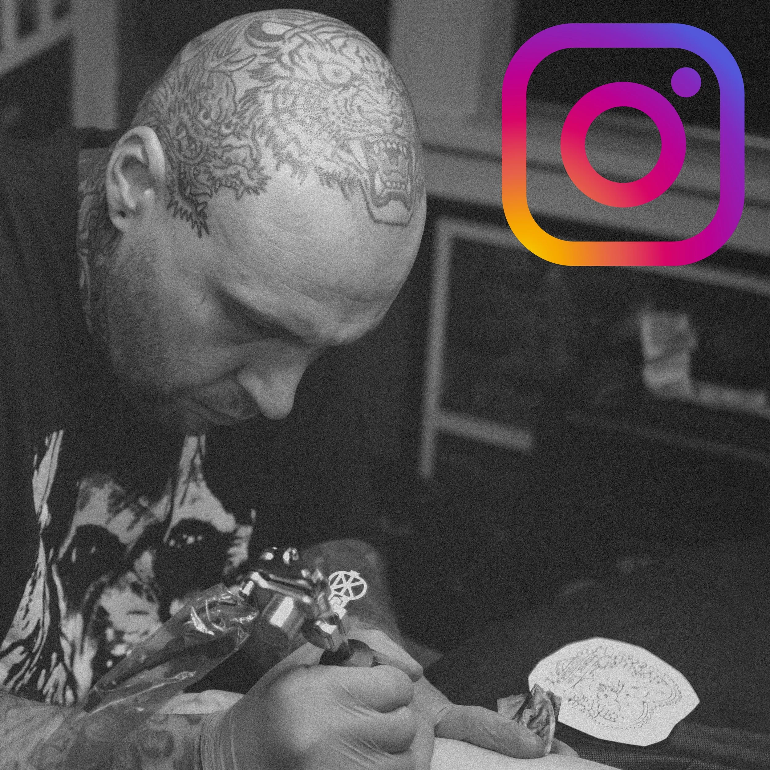 A person with a shaved head and a detailed tattoo of a tiger on topof their head. There is a large light-up Instagram logo overlayed on the right side of the image, and some paper items are in the foreground.