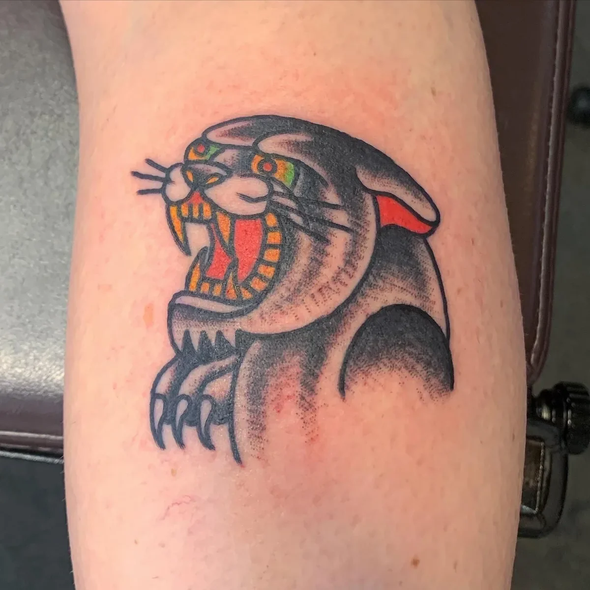 Classic American Traditional panther head tattoo with bold black shading and bright color accents. 