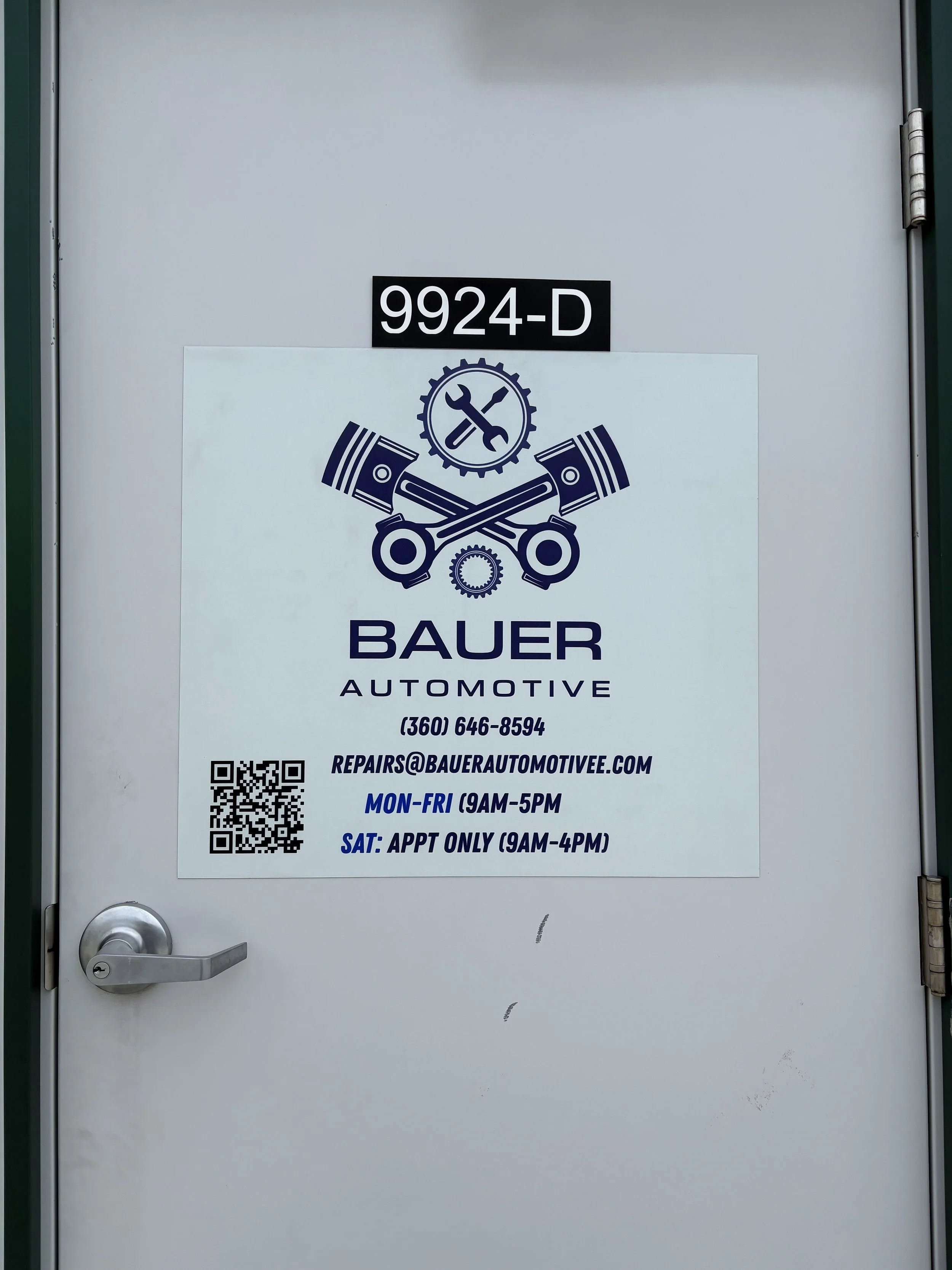 Bauer Automotive entrance door displaying shop hours, phone number, and contact information.