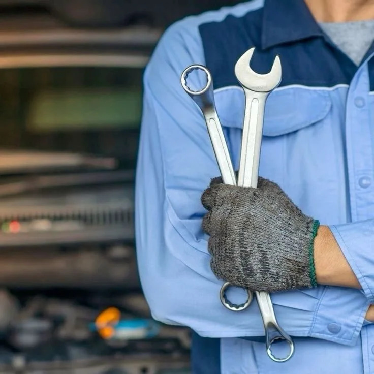 Bauer automotive mechanic holding wrenches ready for vehicle maintenance and repair work.