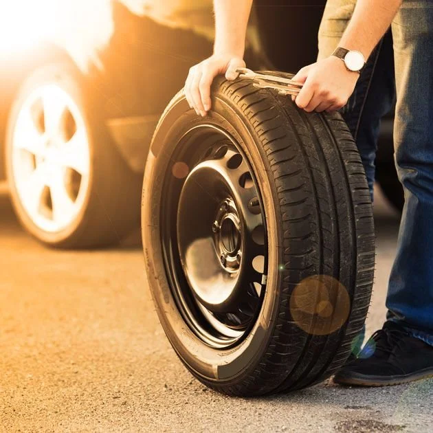 Technician installing a new tire during roadside service and tire replacement.