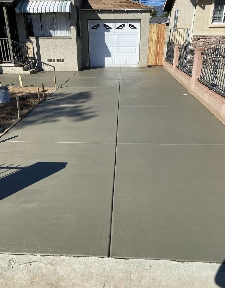 Freshly poured concrete driveway in front of a garage.