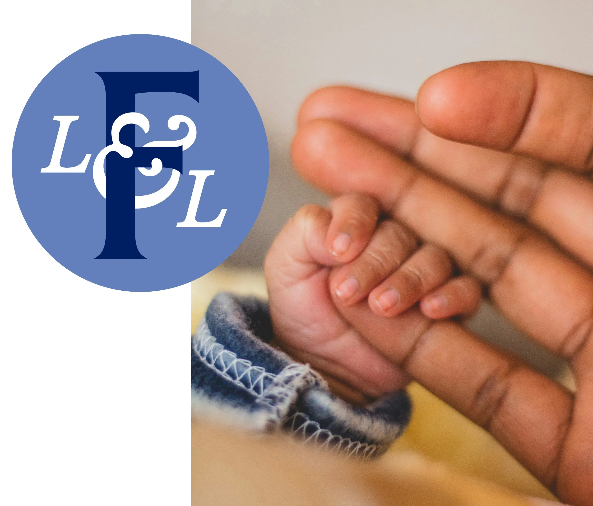 Close-up of a person's hand holding two fingers, with a background that includes a blue circle with white and dark blue letters spelling 'LET' and a grey scarf or clothing item with a white and blue pattern.