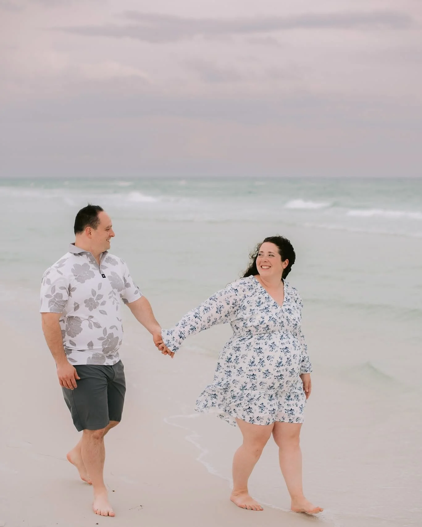 Adam and kristen Ladenburger holding hands while walking on a beach